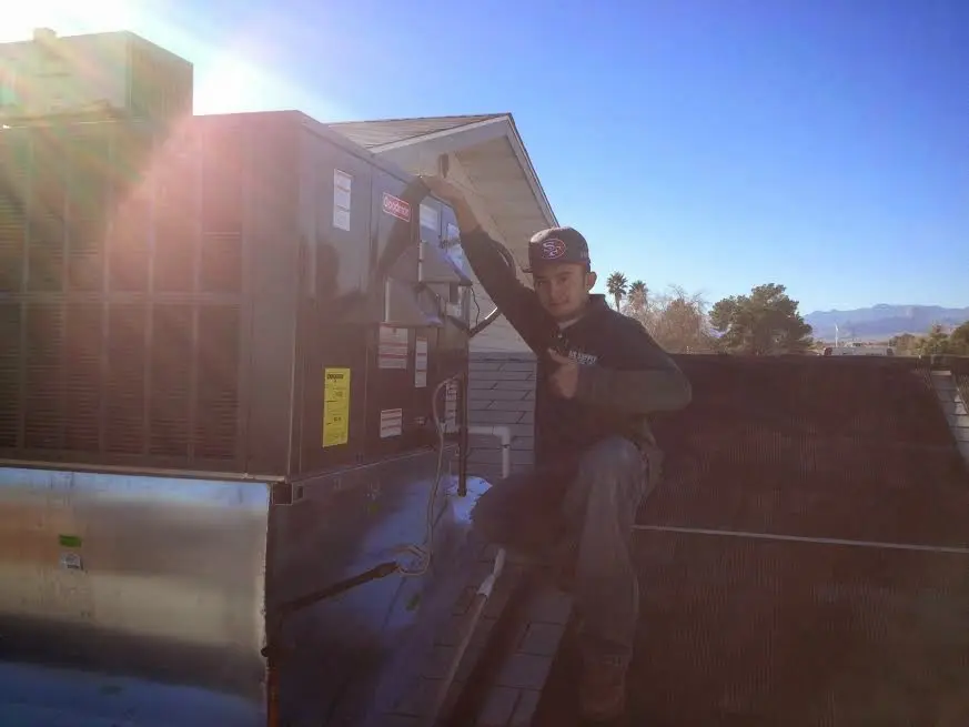 HVAC technician performing Heat Pump Repair on a rooftop unit in Fayetteville
